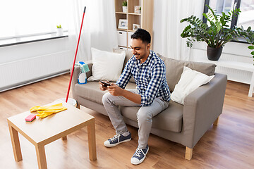 Image showing man playing game on smartphone after cleaning home