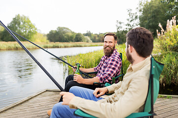 Image showing male friends fishing and drinking beer on lake