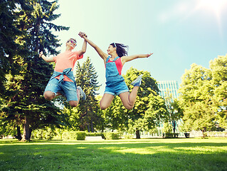 Image showing happy teenage couple jumping at summer park