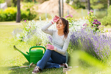 Image showing tired young woman with garden tools in summer