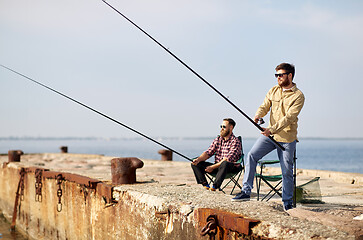 Image showing happy friends with fishing rods on pier