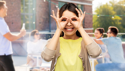 Image showing asian woman making finger glasses at rooftop party