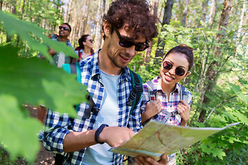 Image showing friends with map and backpacks hiking in forest