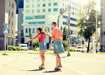 Image showing teenage couple riding skateboards on city street