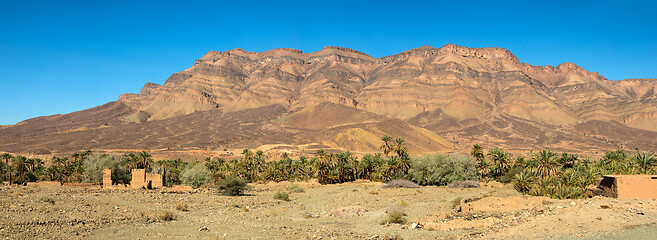 Image showing Moroccan clay houses near mountains and palms