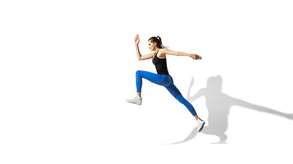 Image showing Beautiful young female athlete stretching on white studio background with shadows