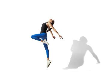 Image showing Beautiful young female athlete stretching on white studio background with shadows