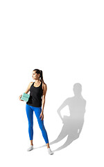 Image showing Beautiful young female athlete stretching on white studio background with shadows