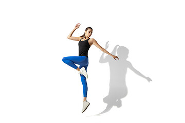 Image showing Beautiful young female athlete stretching on white studio background with shadows