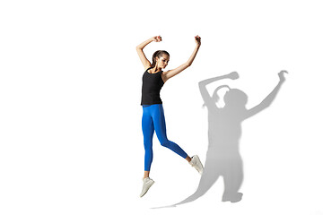 Image showing Beautiful young female athlete stretching on white studio background with shadows