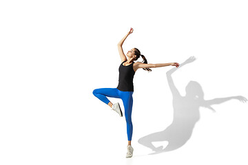 Image showing Beautiful young female athlete stretching on white studio background with shadows