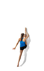 Image showing Beautiful young female athlete stretching on white studio background with shadows