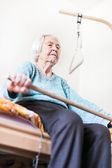 Image showing Elderly 96 years old woman exercising with a stick sitting on her bad.