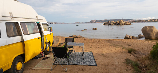 Image showing Old colorful retro camper van on camping site at beautiful rocky coastal landscape of Costa Smeralda, north east Sardinia, Italy. Tourism vacation and travel.