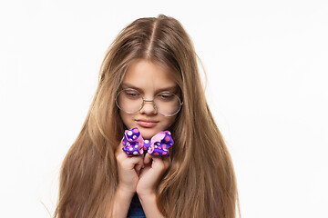 Image showing Girl sadly looks at the blue bow in her hands.