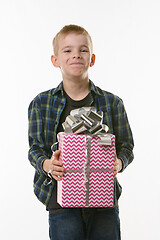 Image showing The boy laughs at the present, holding it in his hands