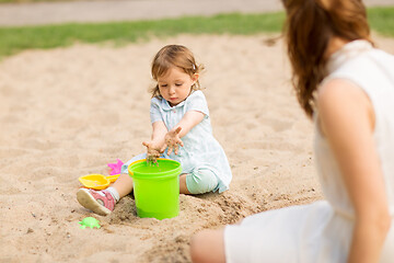 Image showing little baby girl plays with toys in sandbox