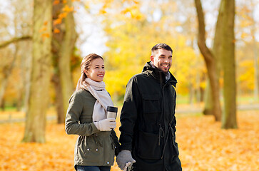 Image showing couple with tumbler walking along autumn park