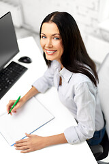 Image showing businesswoman writing to notebook at office