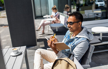 Image showing man with notebook and coffee at street cafe