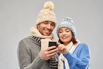 Image showing happy couple in winter clothes with smartphone