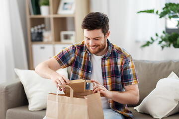 Image showing smiling man unpacking takeaway food at home