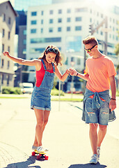 Image showing teenage couple riding skateboards on city street