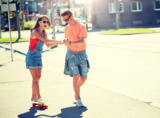 Image showing teenage couple riding skateboards on city street