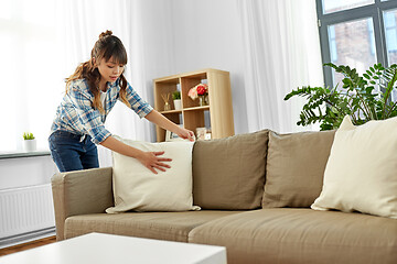 Image showing asian woman arranging sofa cushions at home