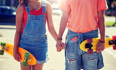 Image showing close up of young couple with skateboards in city