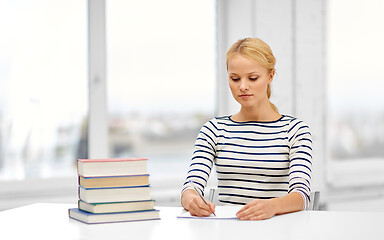 Image showing student woman with books writing to notebook