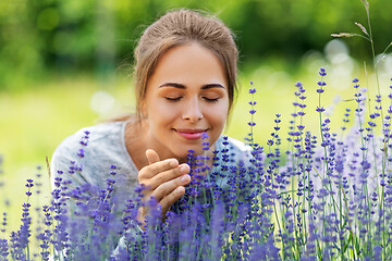 Image showing young woman smelling lavender flowers in garden