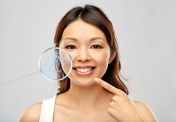 Image showing happy smiling young asian woman touching her face