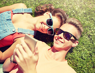 Image showing happy teenage couple smartphone lying on grass