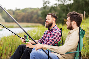 Image showing male friends fishing and drinking beer on lake