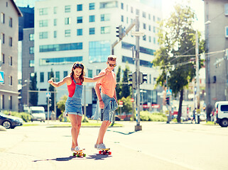 Image showing teenage couple riding skateboards on city street