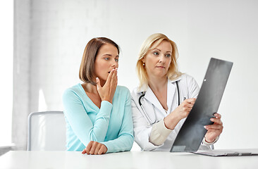 Image showing doctor and sad woman patient with x-ray at clinic