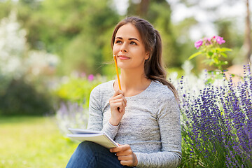 Image showing young woman writing to notebook at summer garden