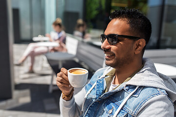 Image showing indian man drinking coffee at city street cafe