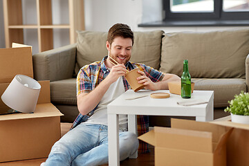 Image showing smiling man eating takeaway food at new home