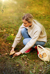 Image showing young woman picking mushrooms in autumn forest