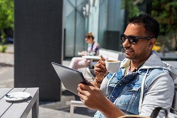 Image showing man with tablet pc drinking coffee at street cafe