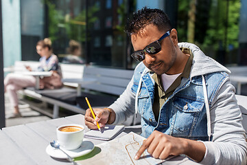 Image showing man with map and notebook at street cafe in city