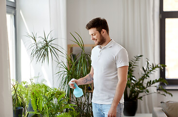 Image showing man spraying houseplants with water at home