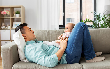 Image showing middle aged father with baby lying on sofa at home