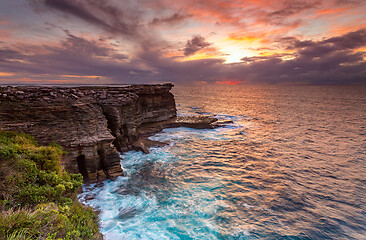 Image showing Sunrise over the ocean and the crumbling headland cliffs 