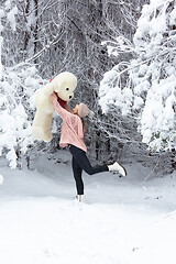 Image showing Happy go lucky woman frolicking in snow holding large soft toy