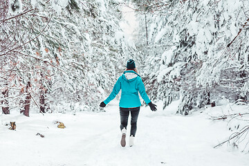 Image showing Woman walking in a snow covered forest