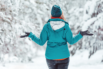 Image showing Woman standing in snow among pine forest with snow falling