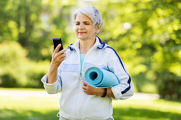 Image showing old woman with exercise mat and smartphone at park